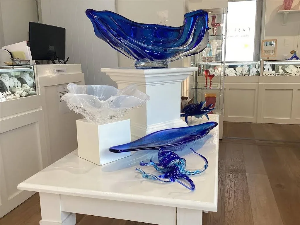 Blue and clear glass sculptures displayed inside Fusion Art Glass & Fine Jewelry.