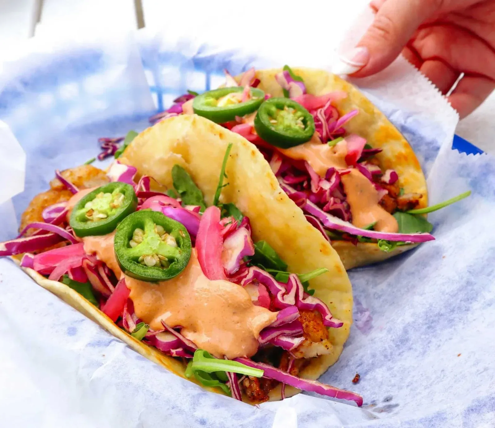 Chiringo tacos topped with slaw, jalapeños, and sauce.
