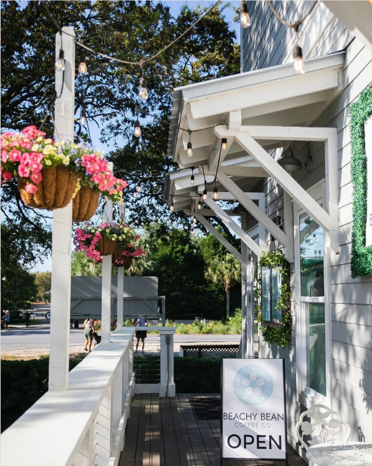 Beachy Bean Coffee Co.’s porch with hanging flowers and its open sign in Seagrove Beach.