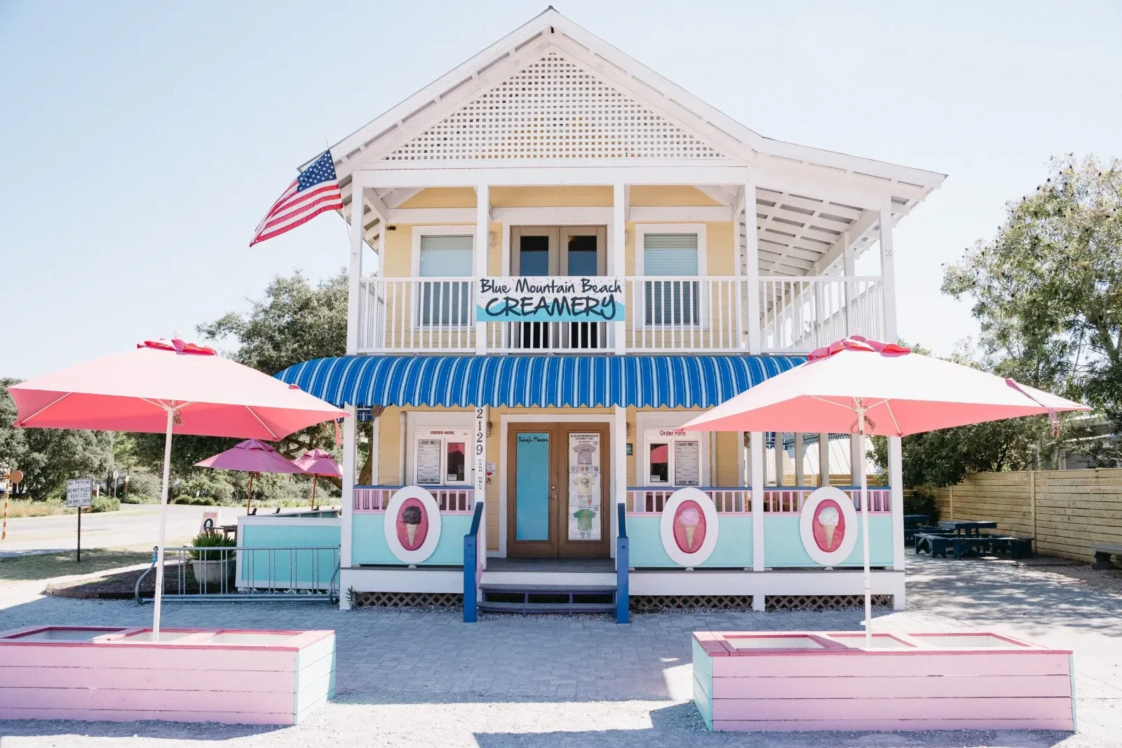 Blue Mountain Beach Creamery storefront with pink umbrellas and outdoor seating.